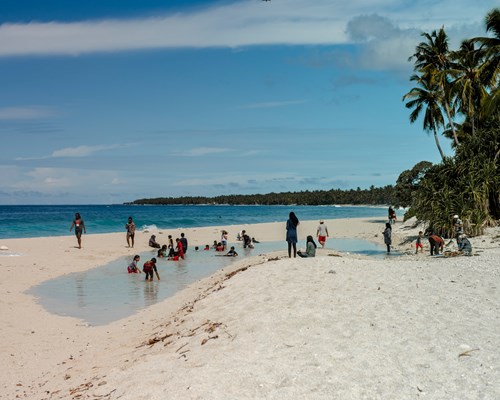 People enjoying a shallow lagoon on a powdery white beach