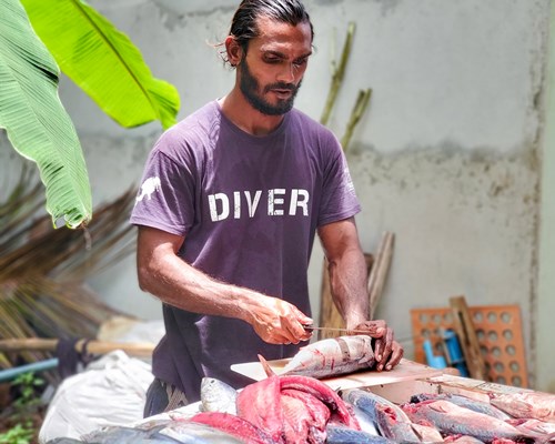 A man cutting fish at a market stall